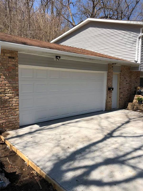 Garage with white door and concrete driveway; brick and siding exterior.