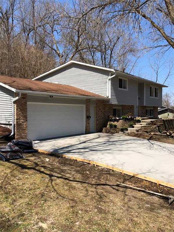Two-story home with a light gray facade, attached garage, and a concrete driveway.