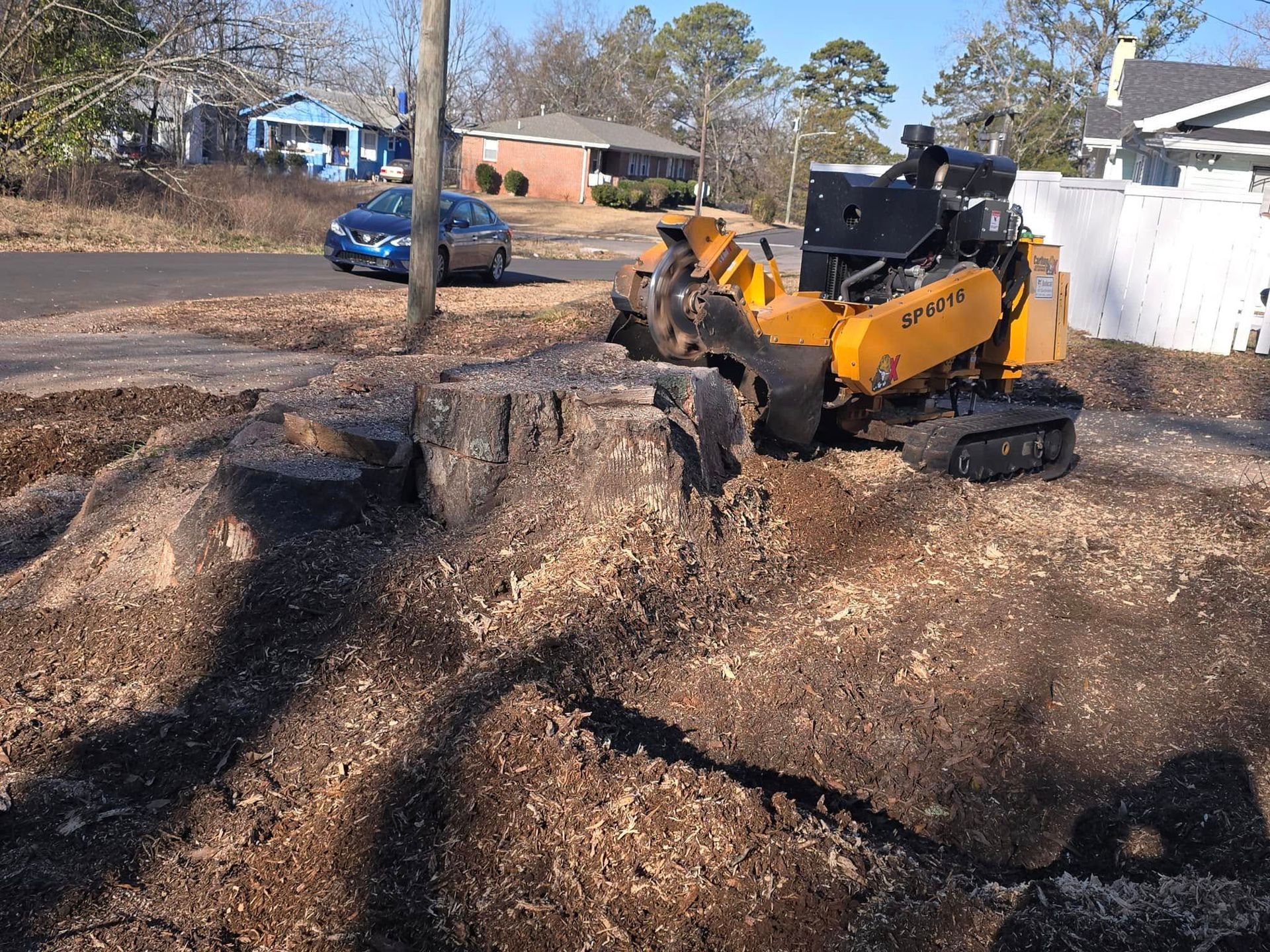 A large tree stump is being removed by an excavator.