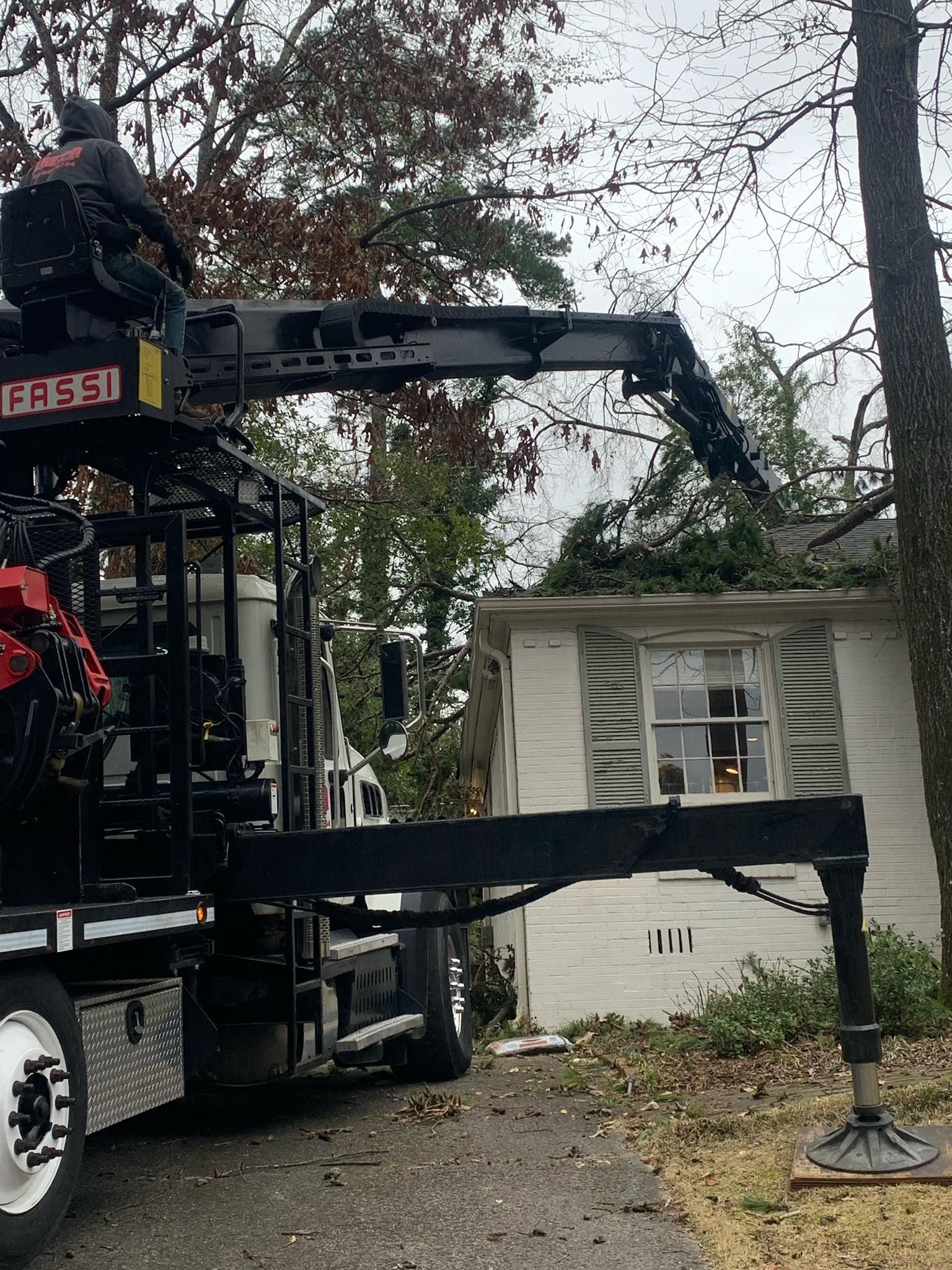 A truck with a crane attached to it is parked in front of a house.