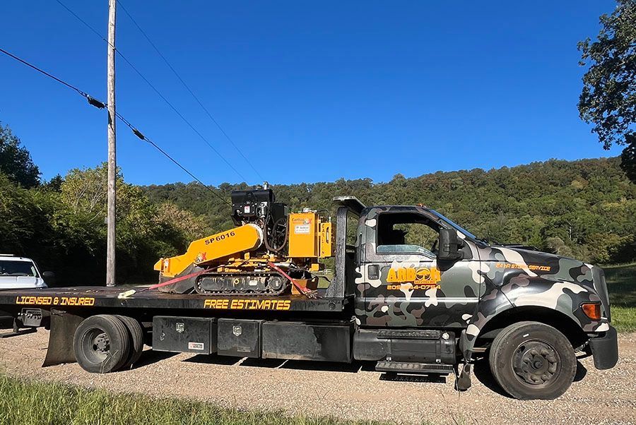 A tow truck with a tractor on the back is parked on the side of the road.
