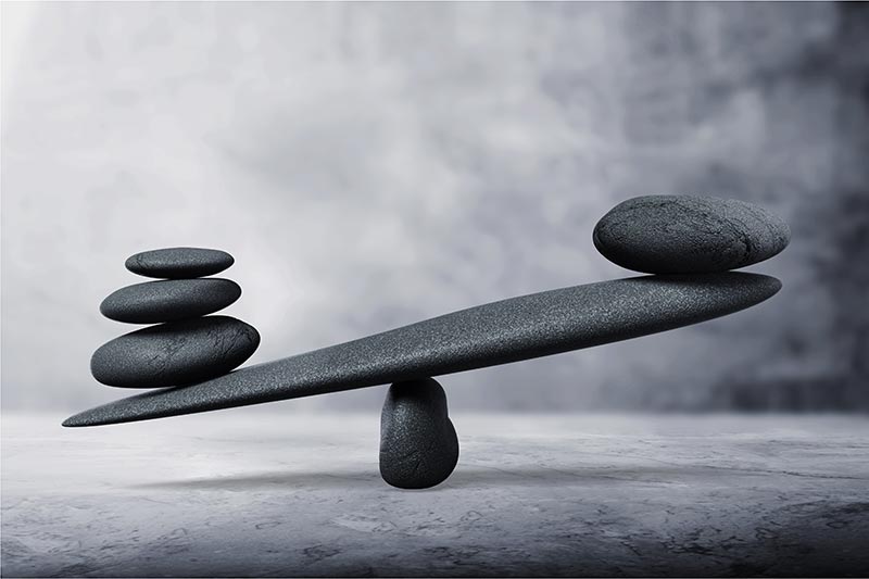 Pietre impilate su una trave di equilibrio; una piccola pila di pietre bilancia una pietra singola più grande.
