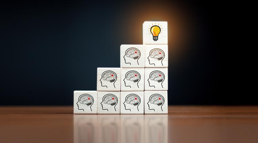 Blocchi impilati come gradini, ognuno con l'icona di un cervello, che portano a un blocco con una lampadina.