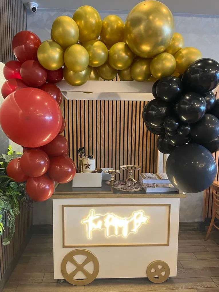 Decorated cart with red, gold, and black balloons, neon sign reading 