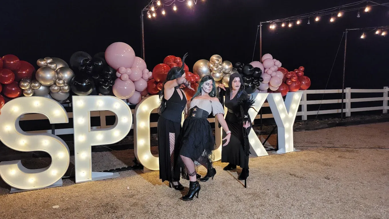 Three people in costumes pose near illuminated 
