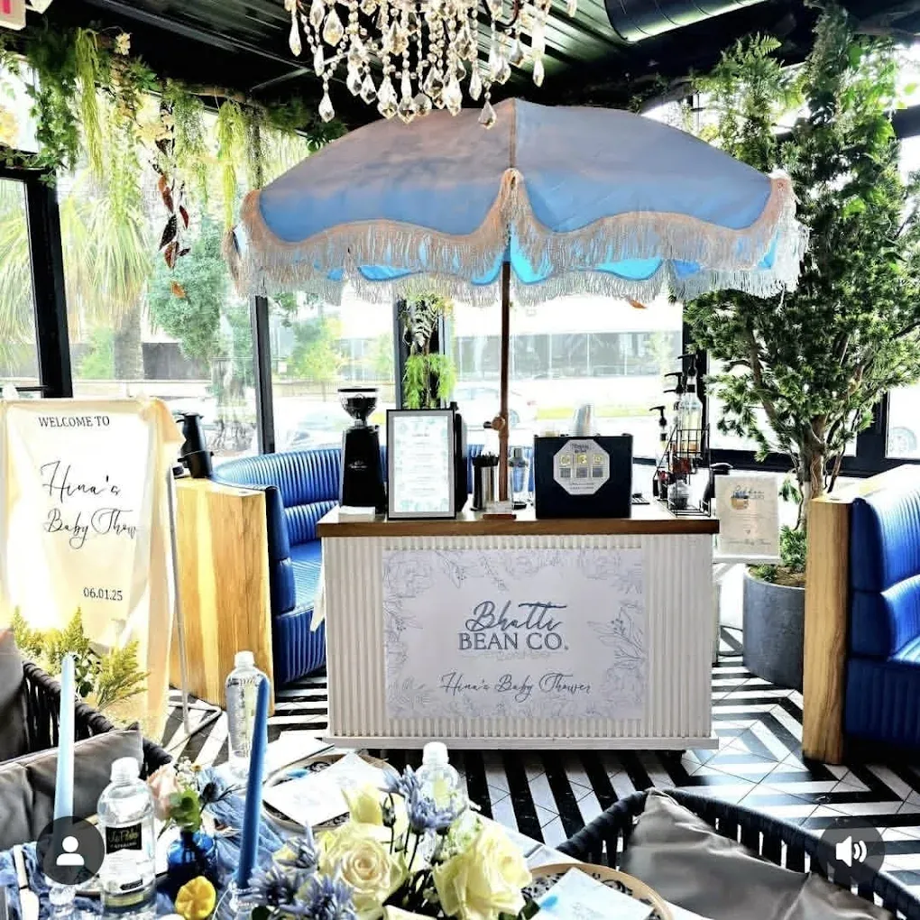 Coffee cart with a blue parasol, indoors with decor, including flowers, a chandelier, and seating.