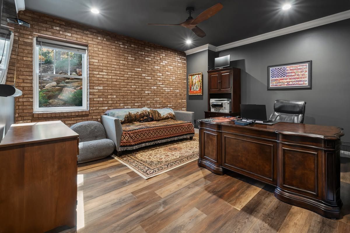 Modern living room with brick accent wall, gray sofa, wood floors, and dark wood cabinet
