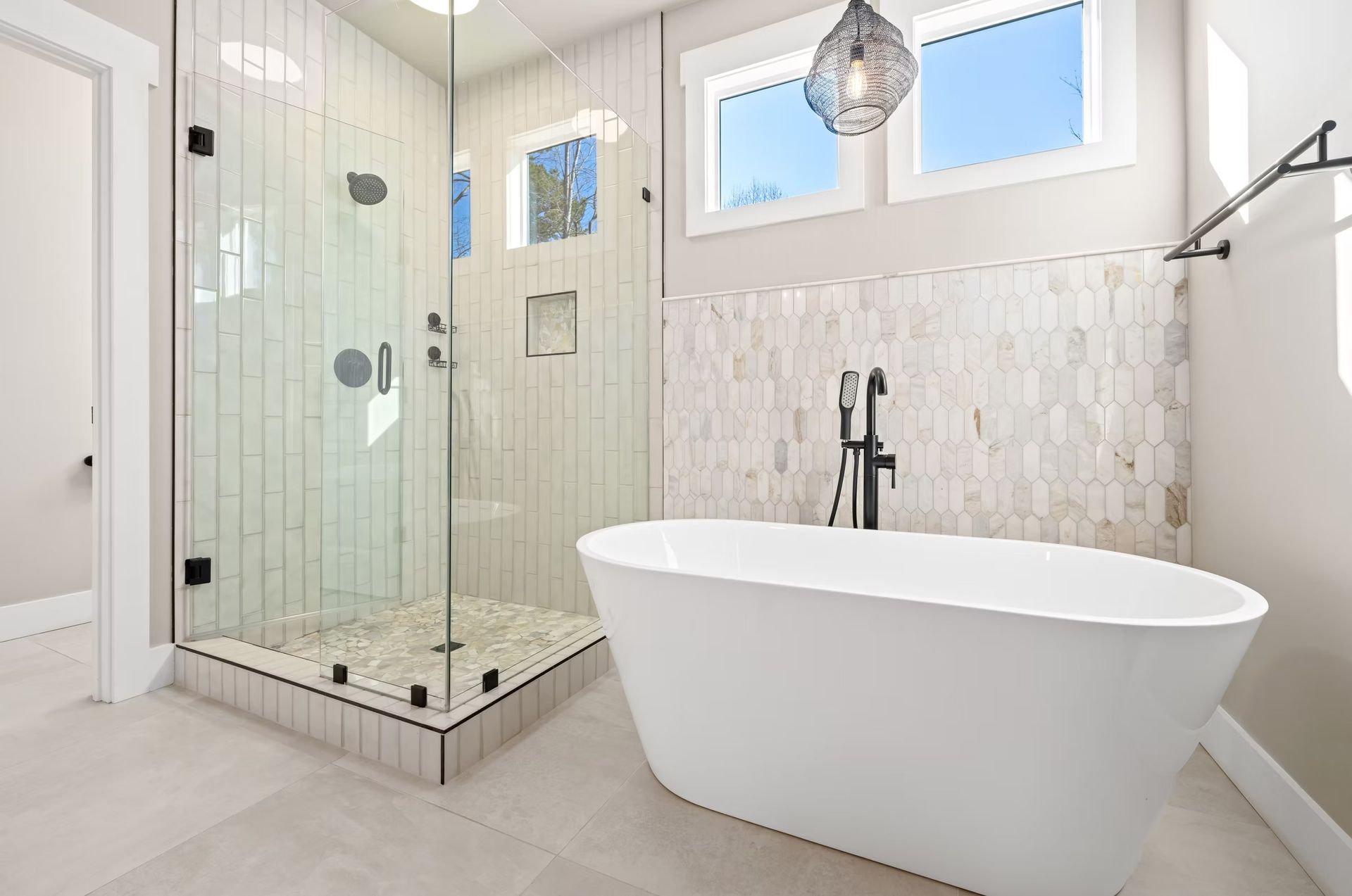 Modern bathroom with a glass shower, freestanding tub, and light tile walls