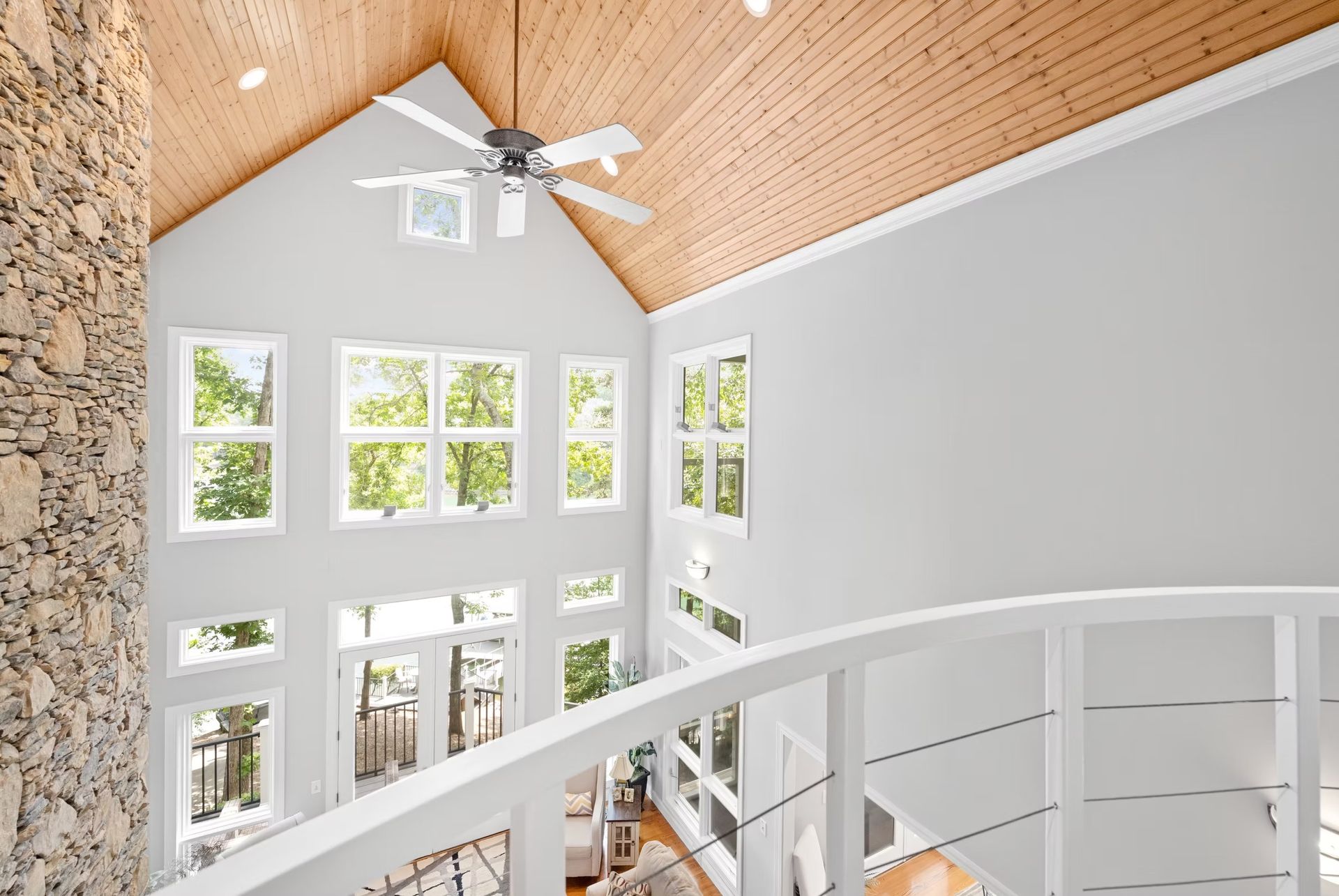 Bright airy atrium with high windows, wood ceiling, white walls, and a curved staircase railing
