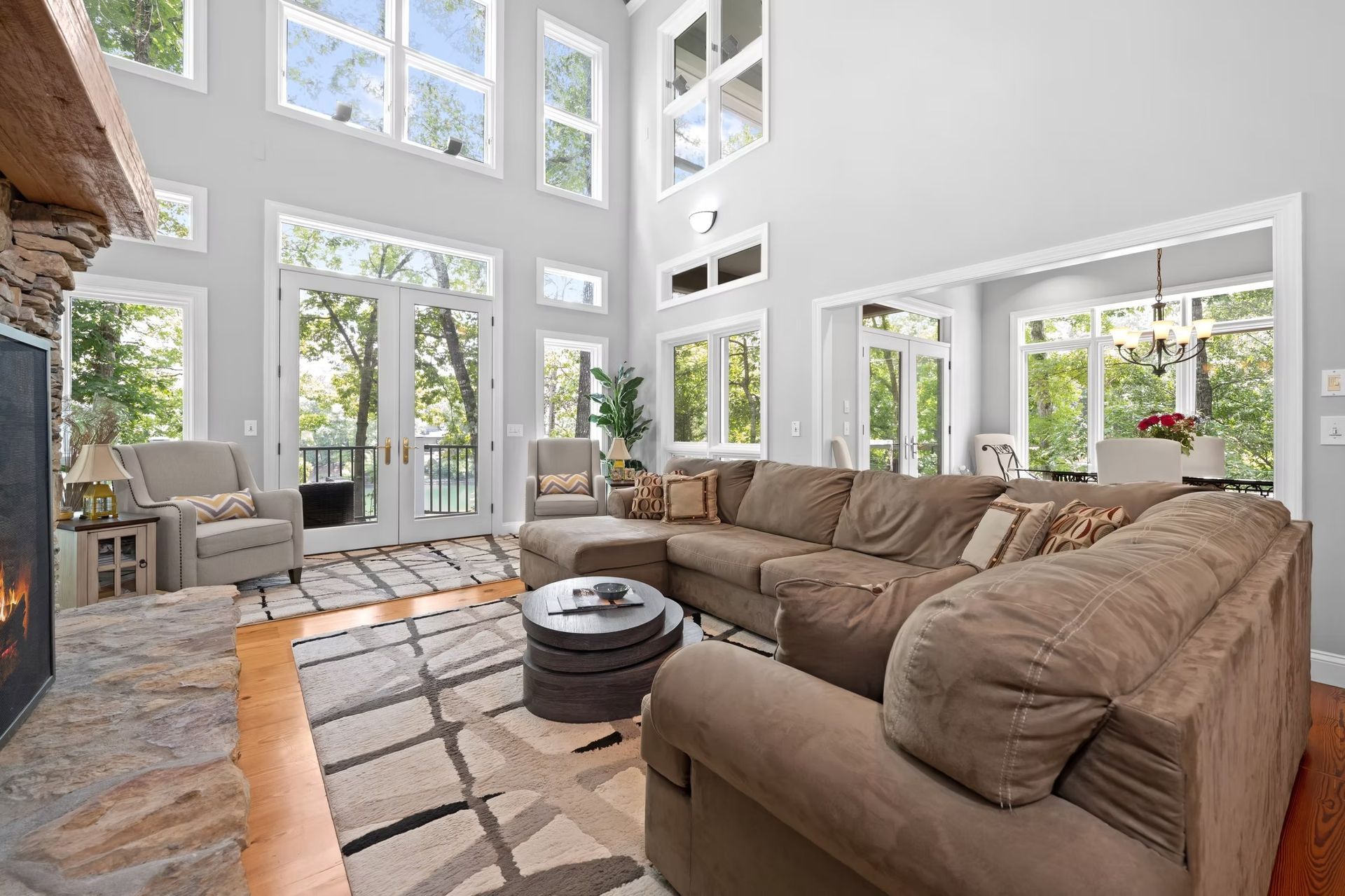 Bright, airy living room with tan sectional sofas, large windows, and a patterned rug in a modern home