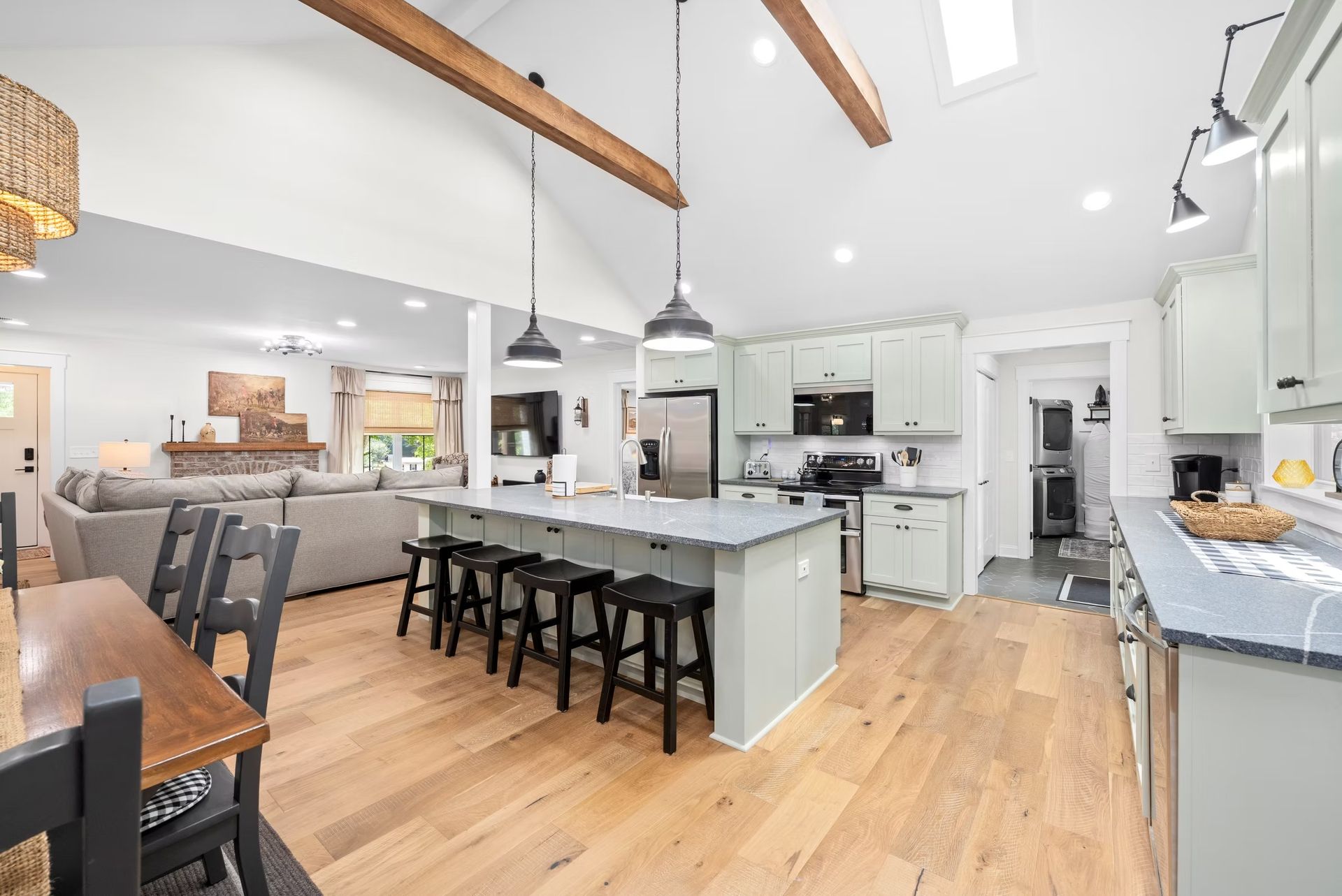Bright modern kitchen with island, pendant lights, wood floors, and adjoining dining area