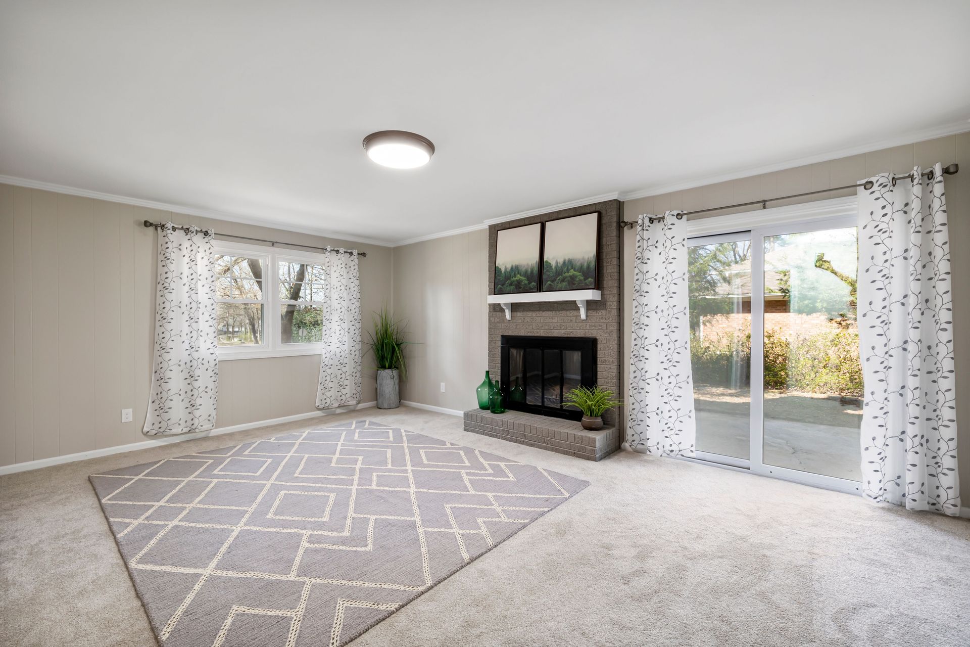 Empty blue bedroom with white ceiling fan, framed wall art, and striped rug near a white door
