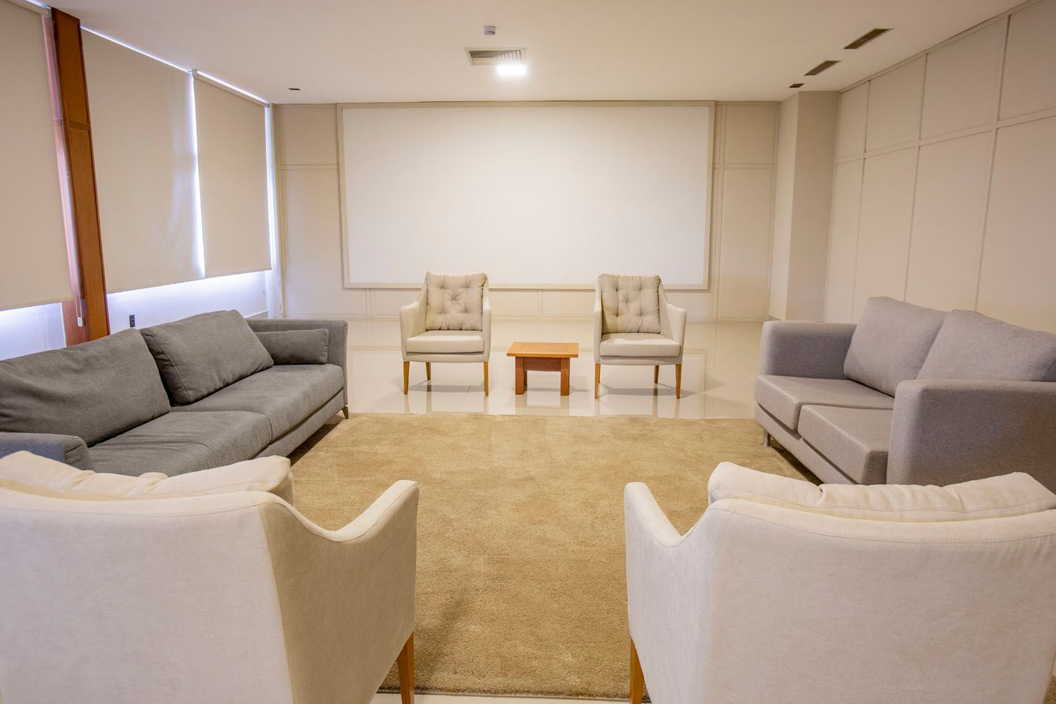 Uma sala de estar cheia de móveis e uma tela de projetor.