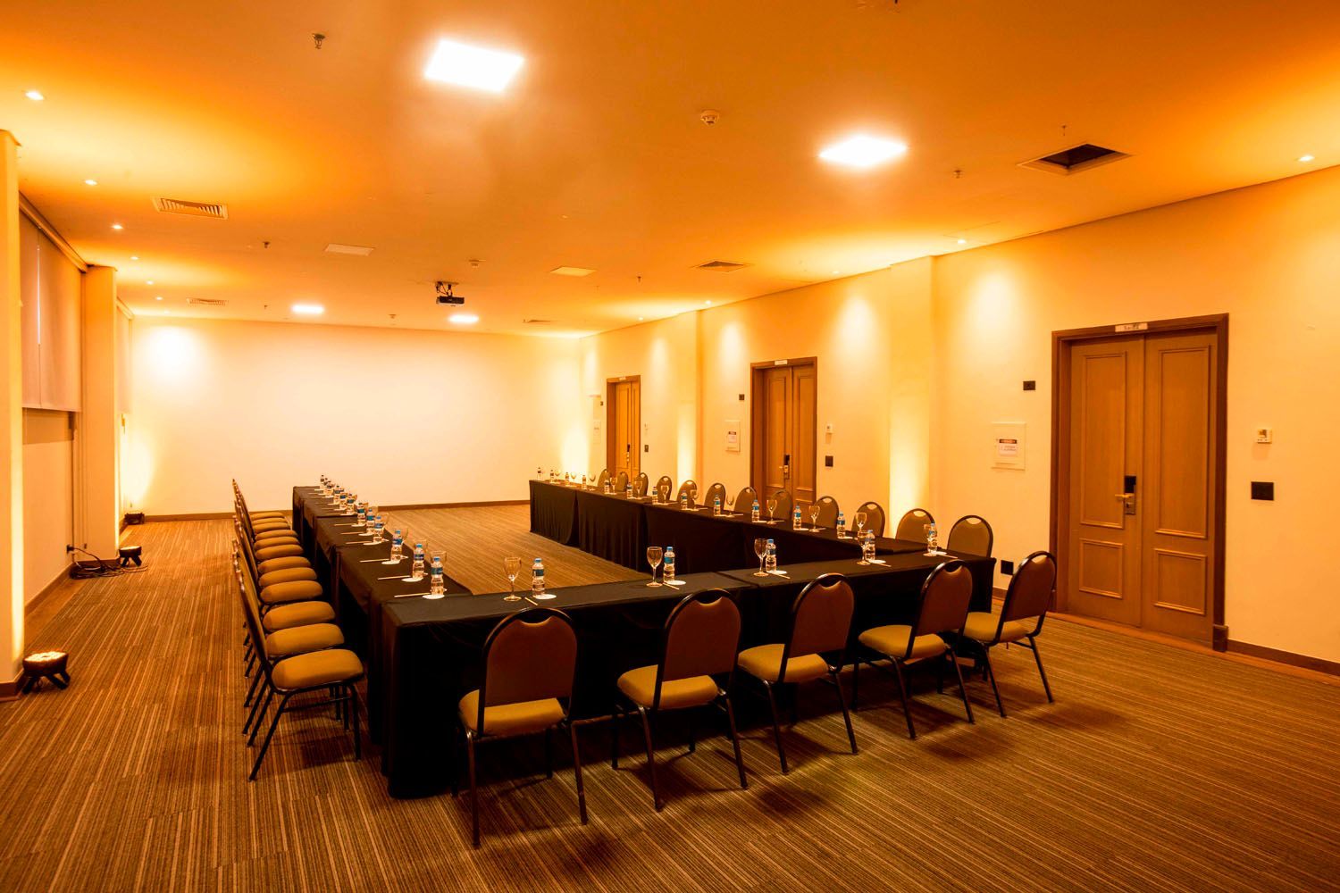 Uma grande sala de conferências com mesas e cadeiras preparadas para uma reunião.