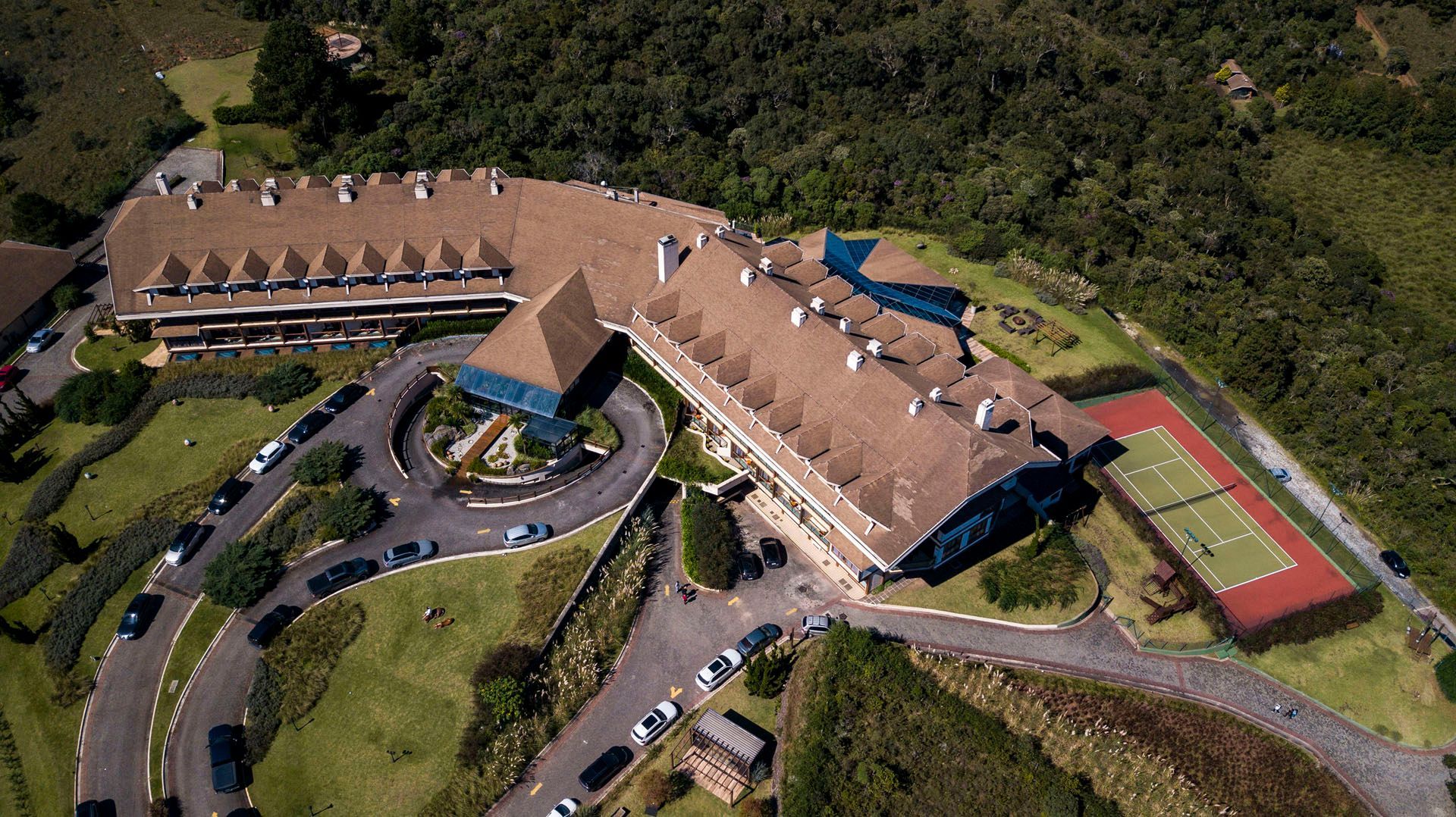 Uma vista aérea de um grande edifício com uma quadra de tênis na frente.
