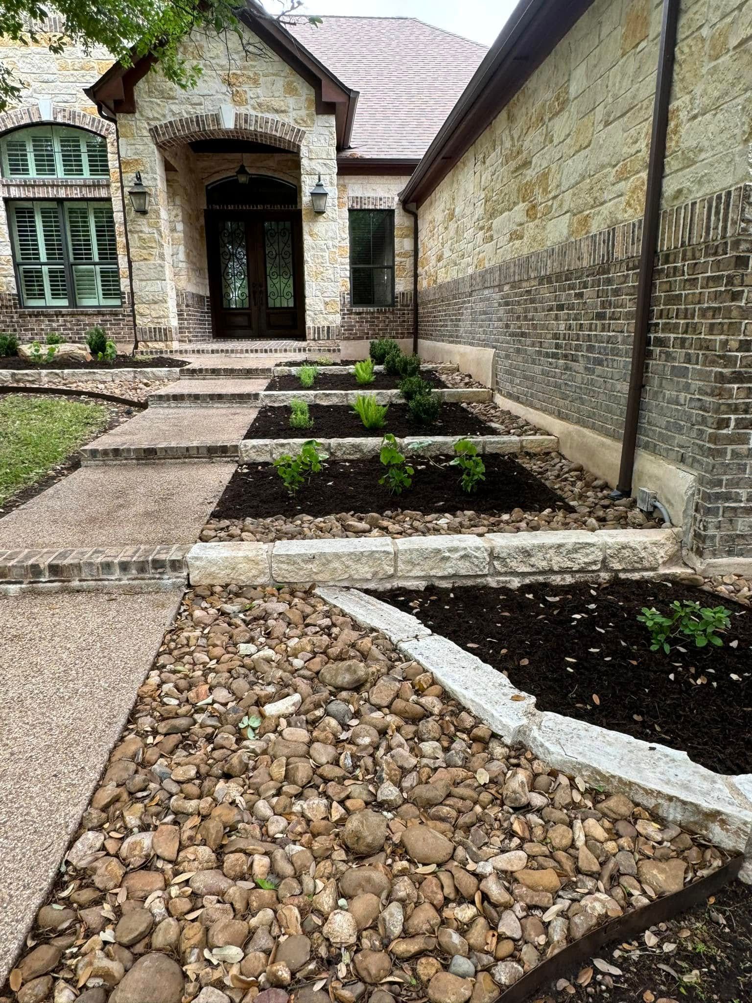 Stone and brick home with landscaped front yard, stone steps, and planted beds.