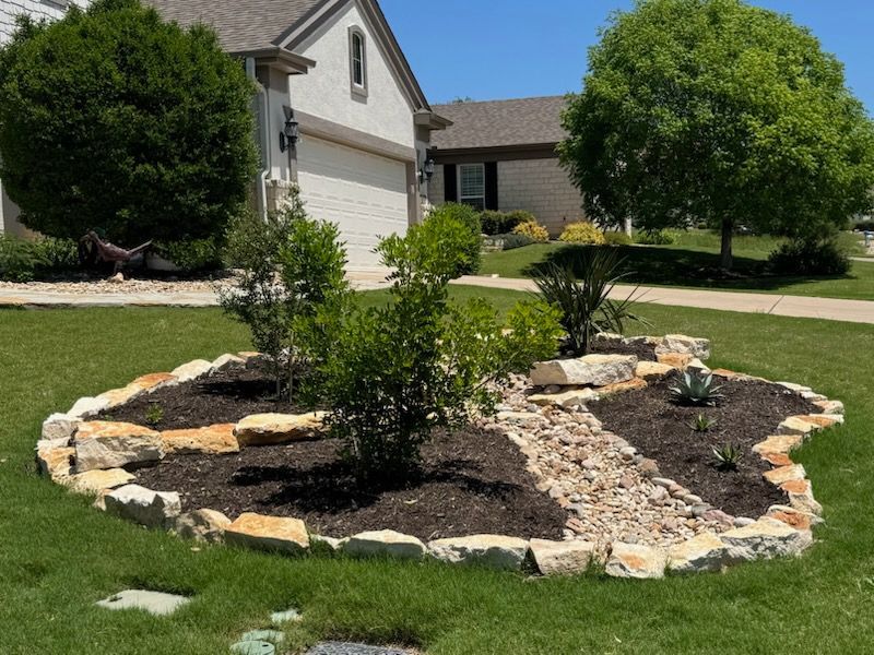 Landscaped front yard with a stone-edged flower bed and mulch.