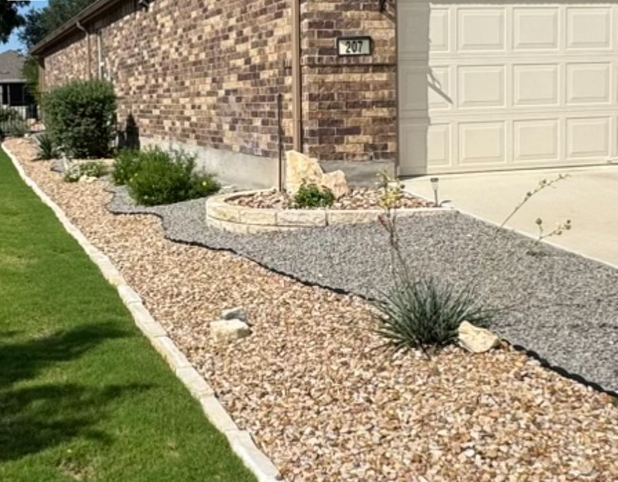 Front yard landscaping with gravel beds, stone edging, and various plants next to a garage.