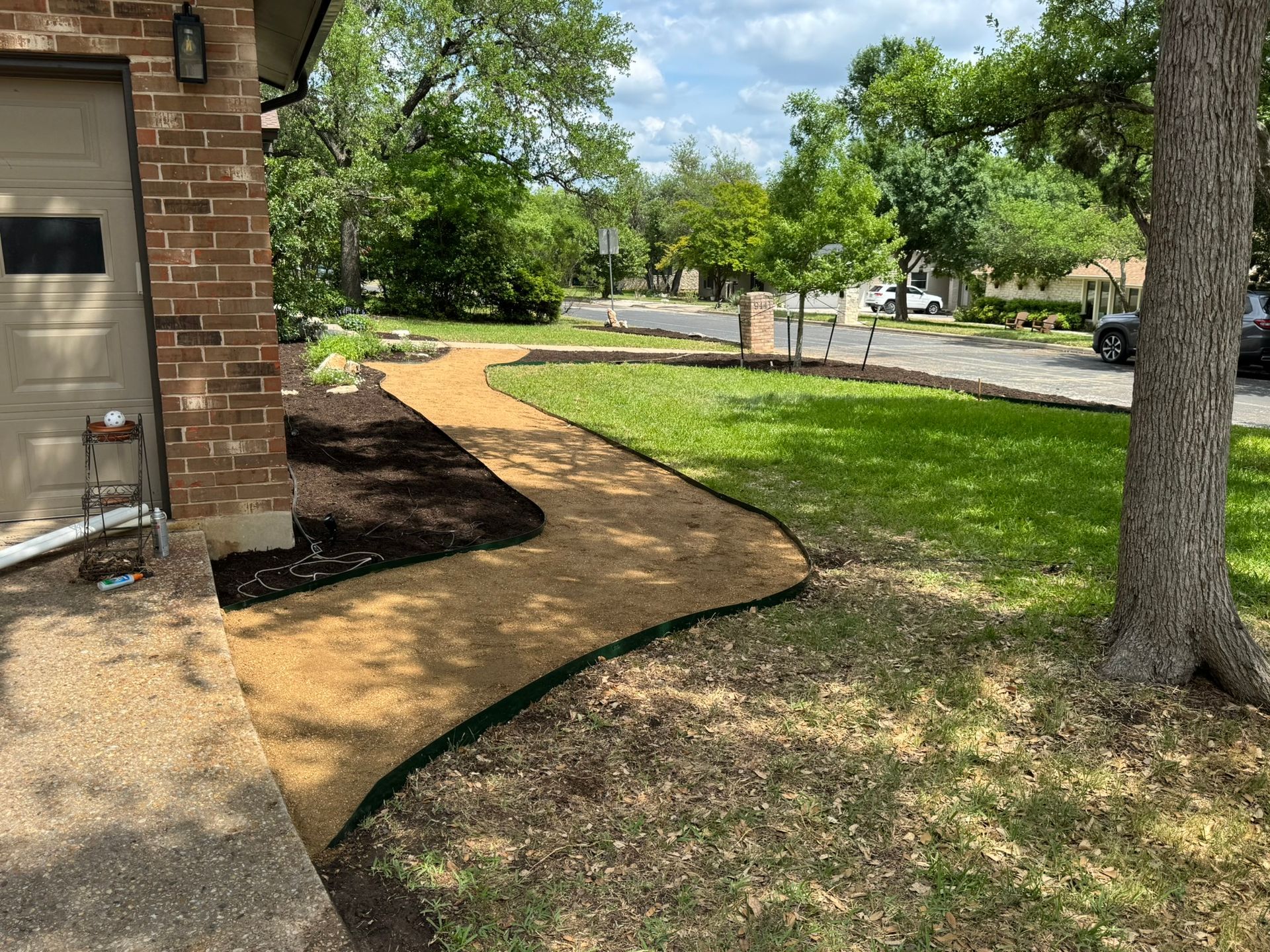 A winding gravel pathway leads from a home's driveway through a grassy yard.
