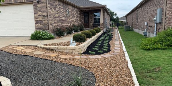 A house exterior with landscaped walkway, featuring mulch and stepping stones.