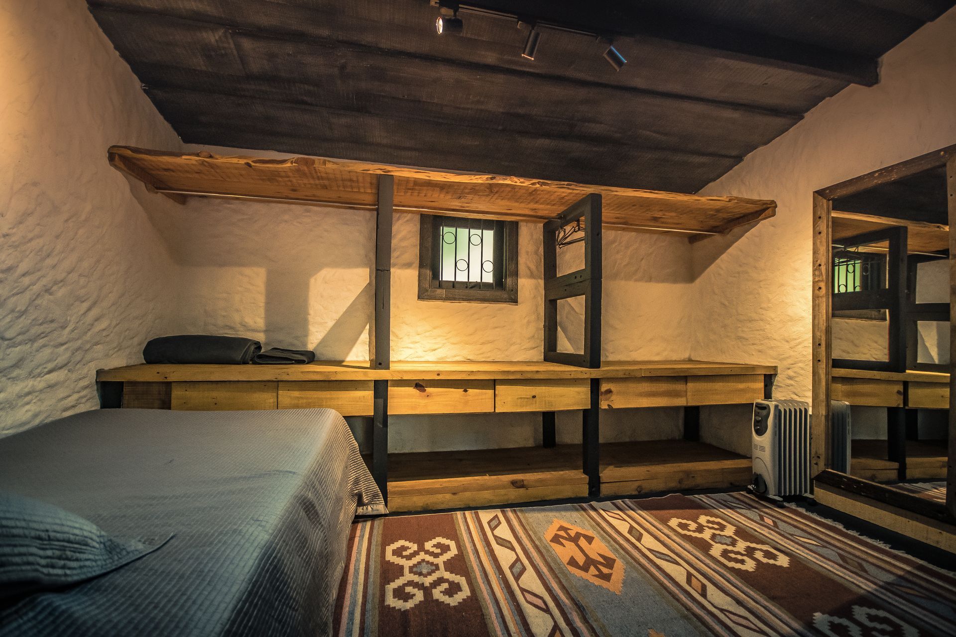 Um quarto com cama, prateleiras e espelho.