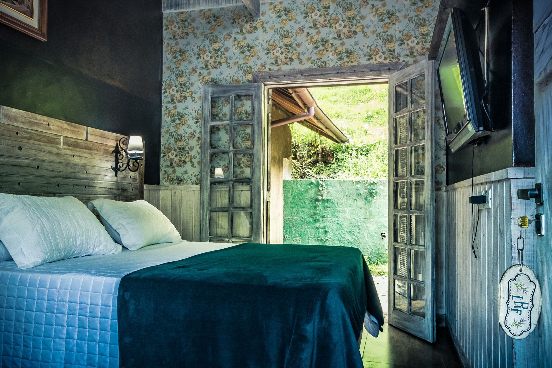 Um quarto com cama, televisão e portas de vidro deslizantes.