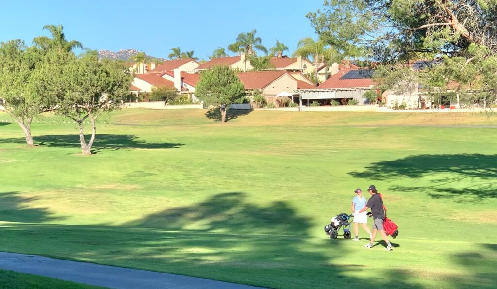 A couple of people are walking on a golf course.