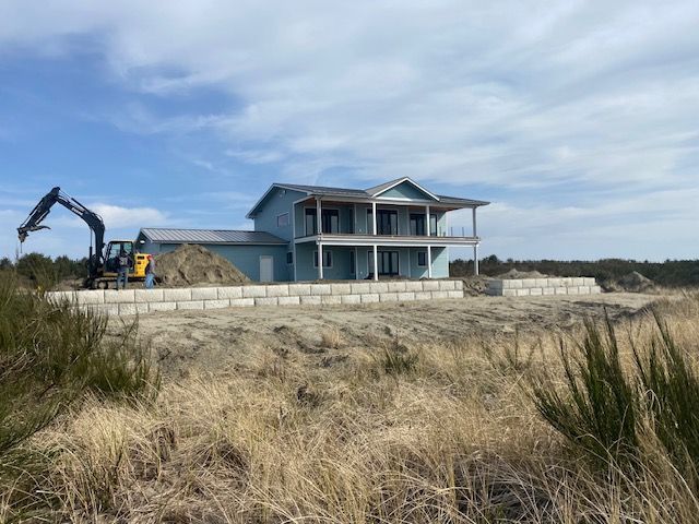 A large house is being built in a field with a bulldozer in the foreground.
