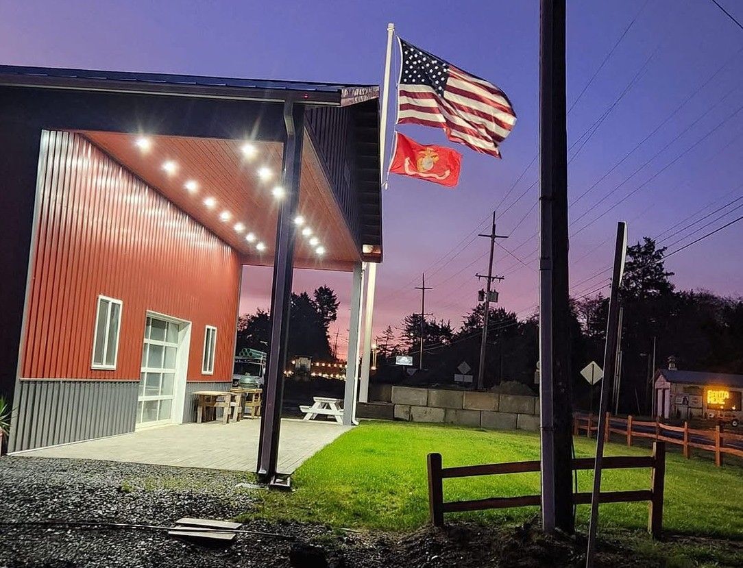 Three american flags are flying in front of a building at night.