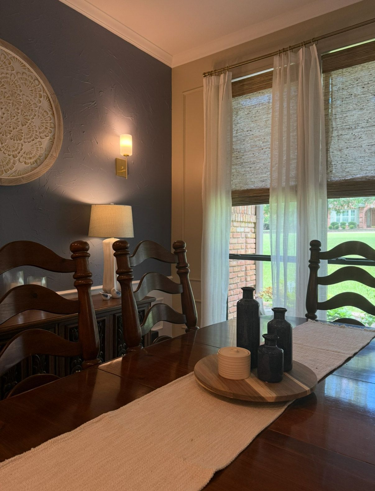 Dining room with table, chairs, blue wall, art, and natural light from window.