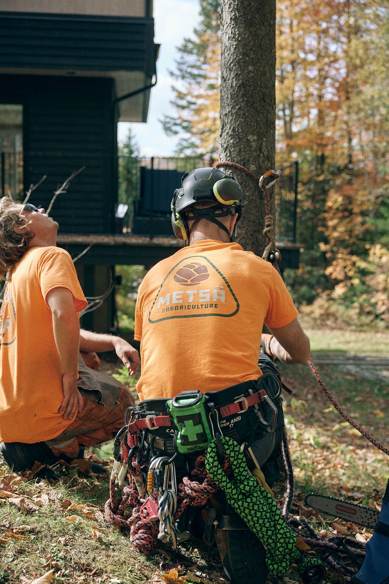 Deux hommes en chemises orange sont assis à côté d'un arbre.