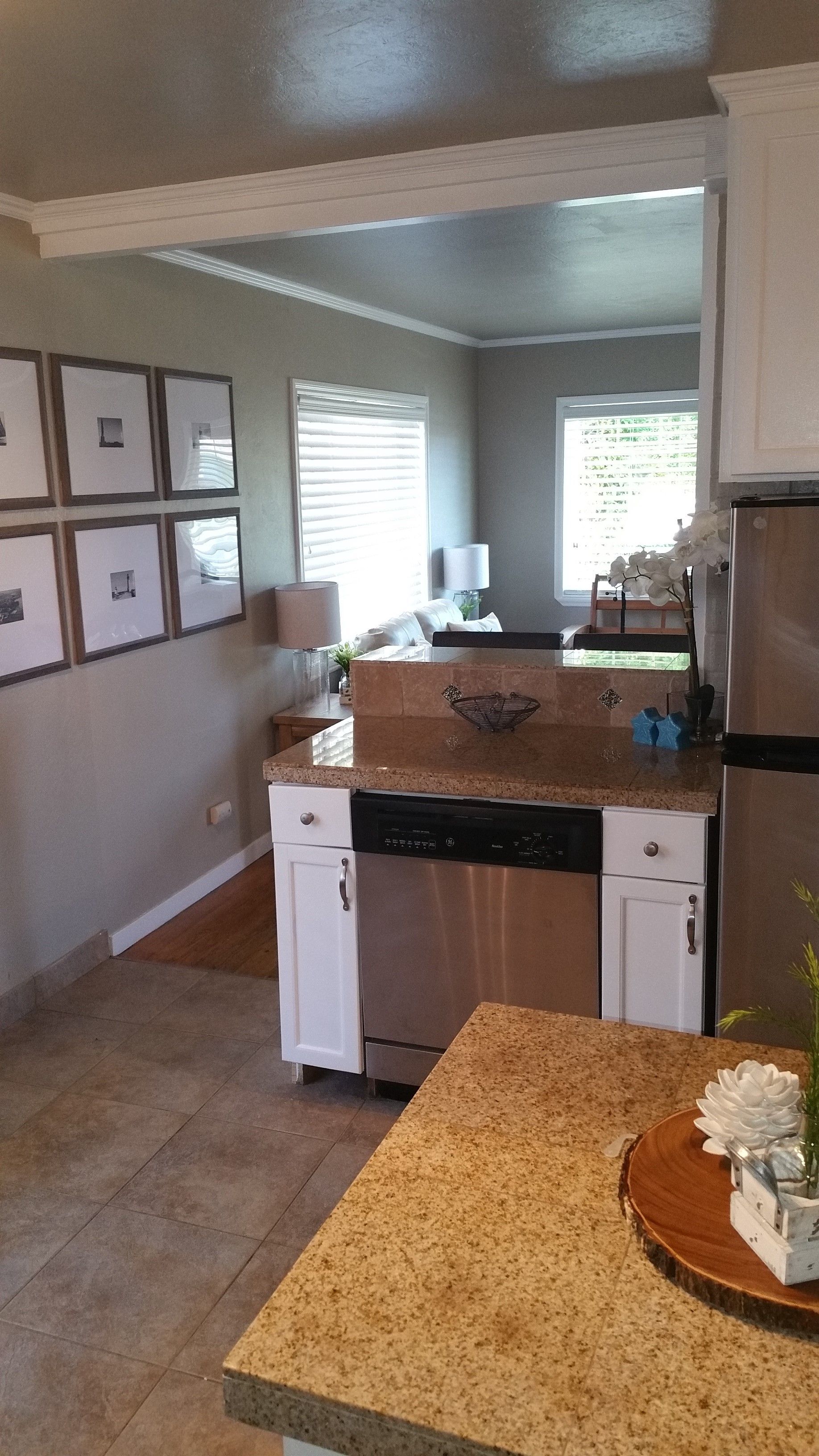 Bright kitchen with granite counters, white appliances, and framed wall art leading to a sunlit dining area