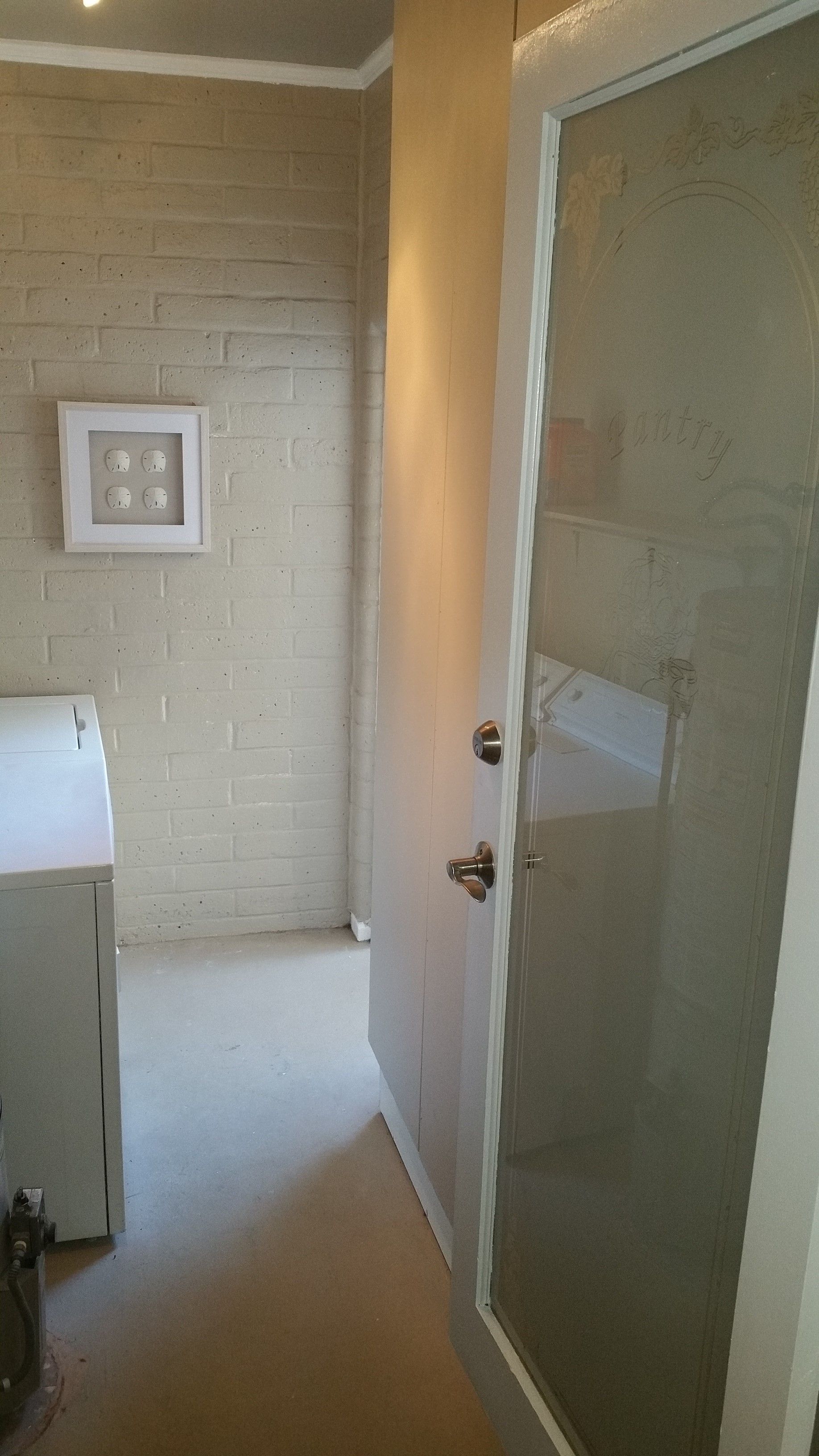 Bathroom doorway with frosted glass shower door, beige walls, and a lit wall sconce.