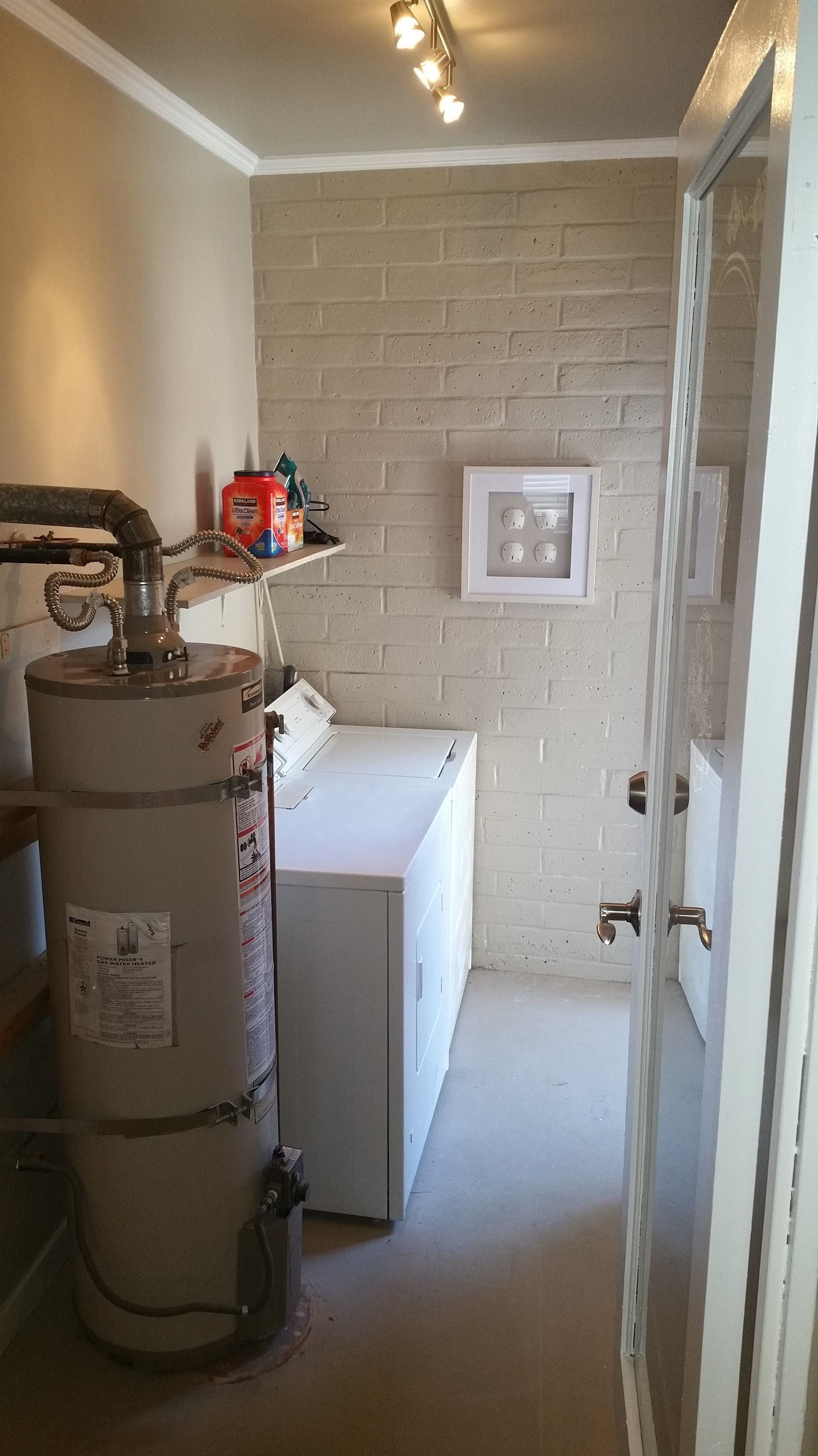 Utility room with water heater, laundry sink, and white washing machine in a narrow space