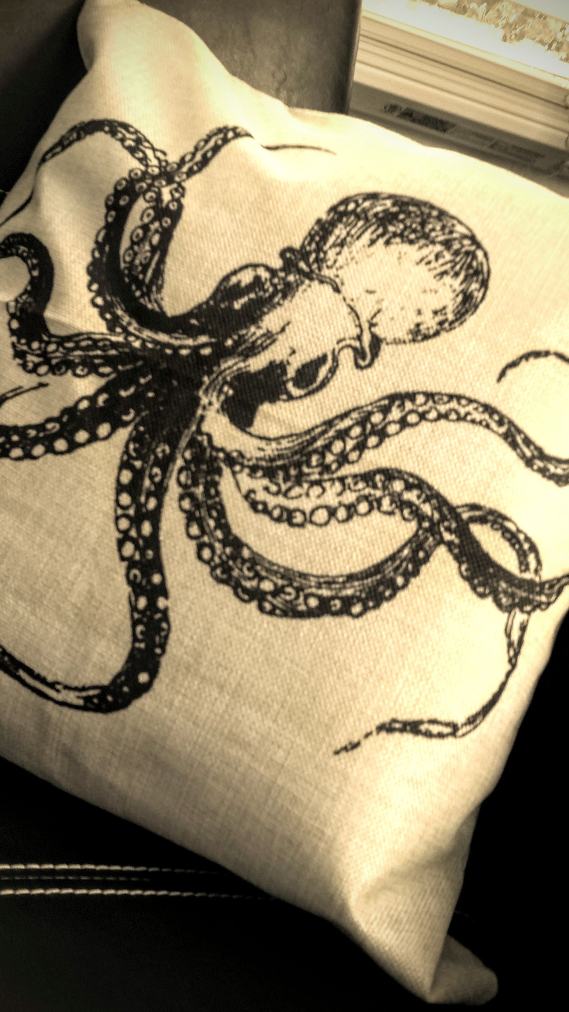 Beige canvas bag with a black octopus illustration on a dark surface
