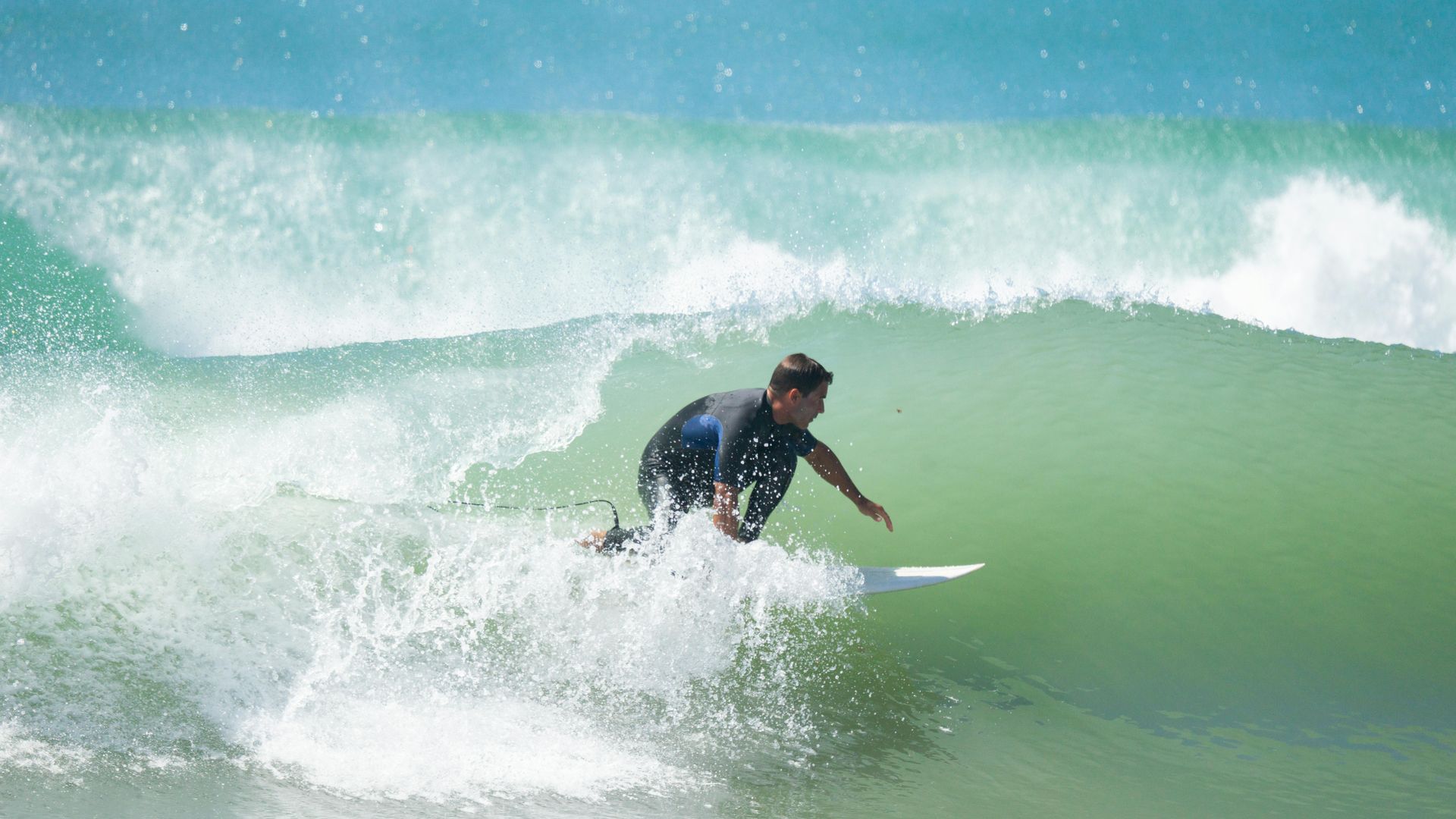 Surfer riding a green wave with white spray in the ocean