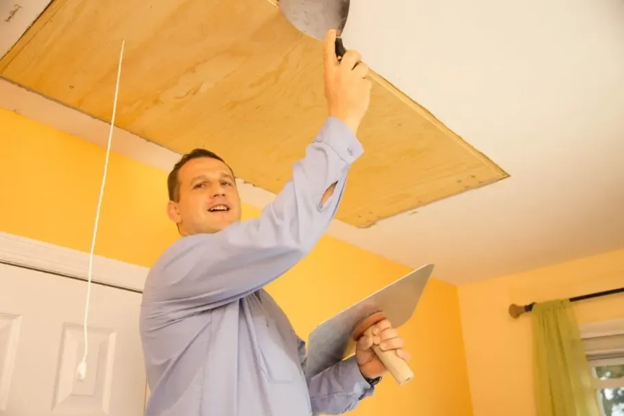 Professional painter applying plaster to a ceiling.