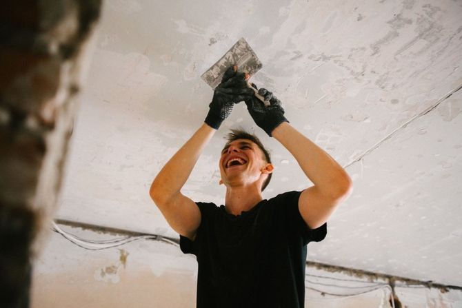 Happy contractor finishing a smooth ceiling surface.