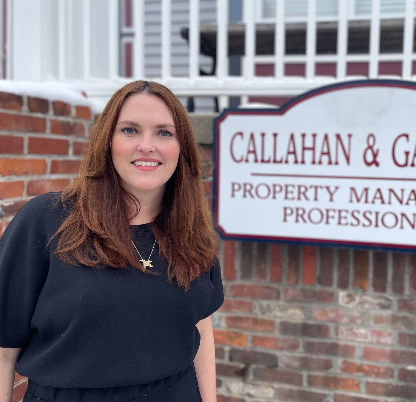 A woman is standing in front of a sign that says callahan & g property mana profession.