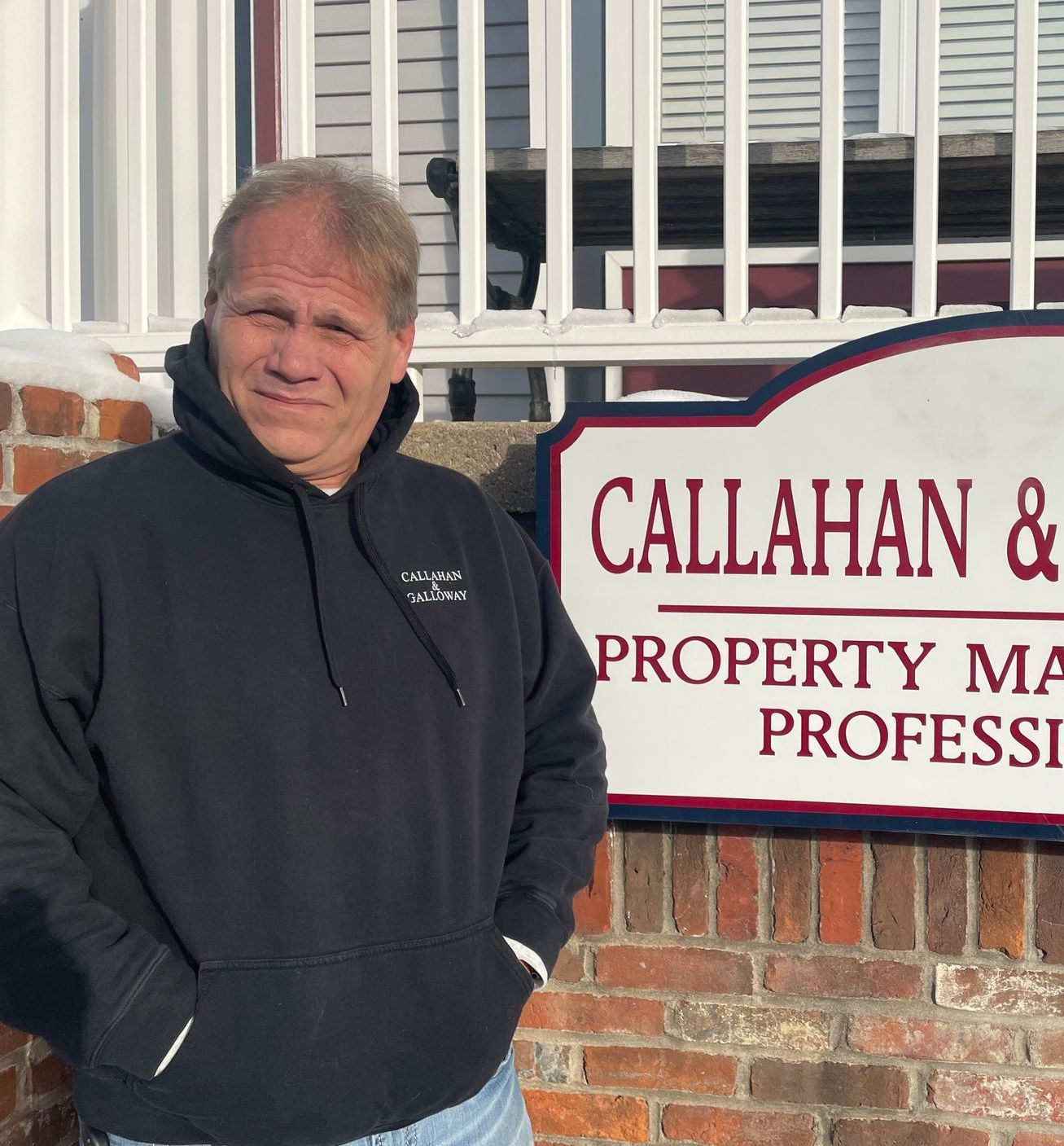 A man stands in front of a callahan & property management sign
