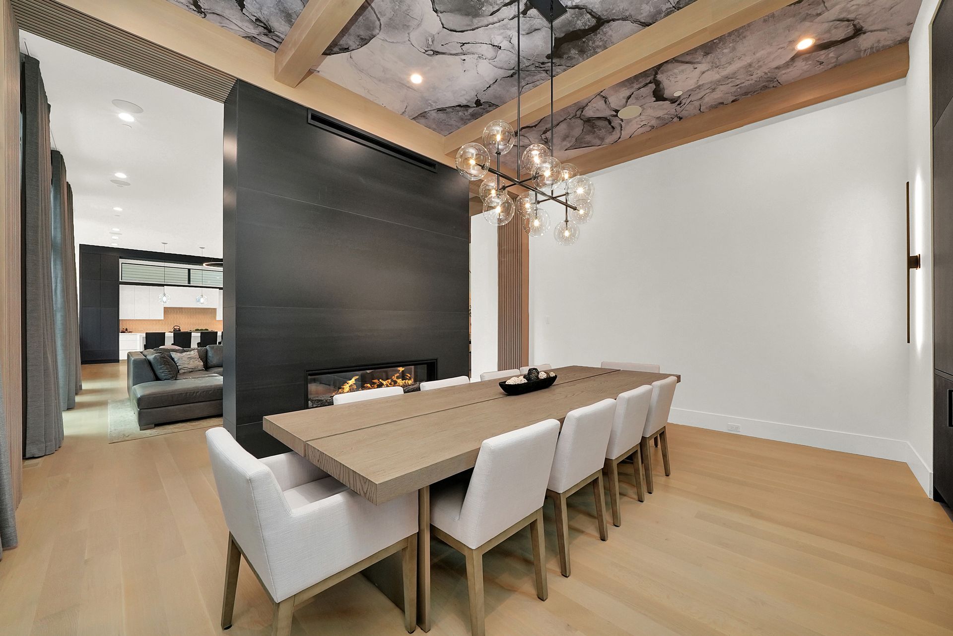 Modern dining room with a long table, white chairs, and a black accent wall