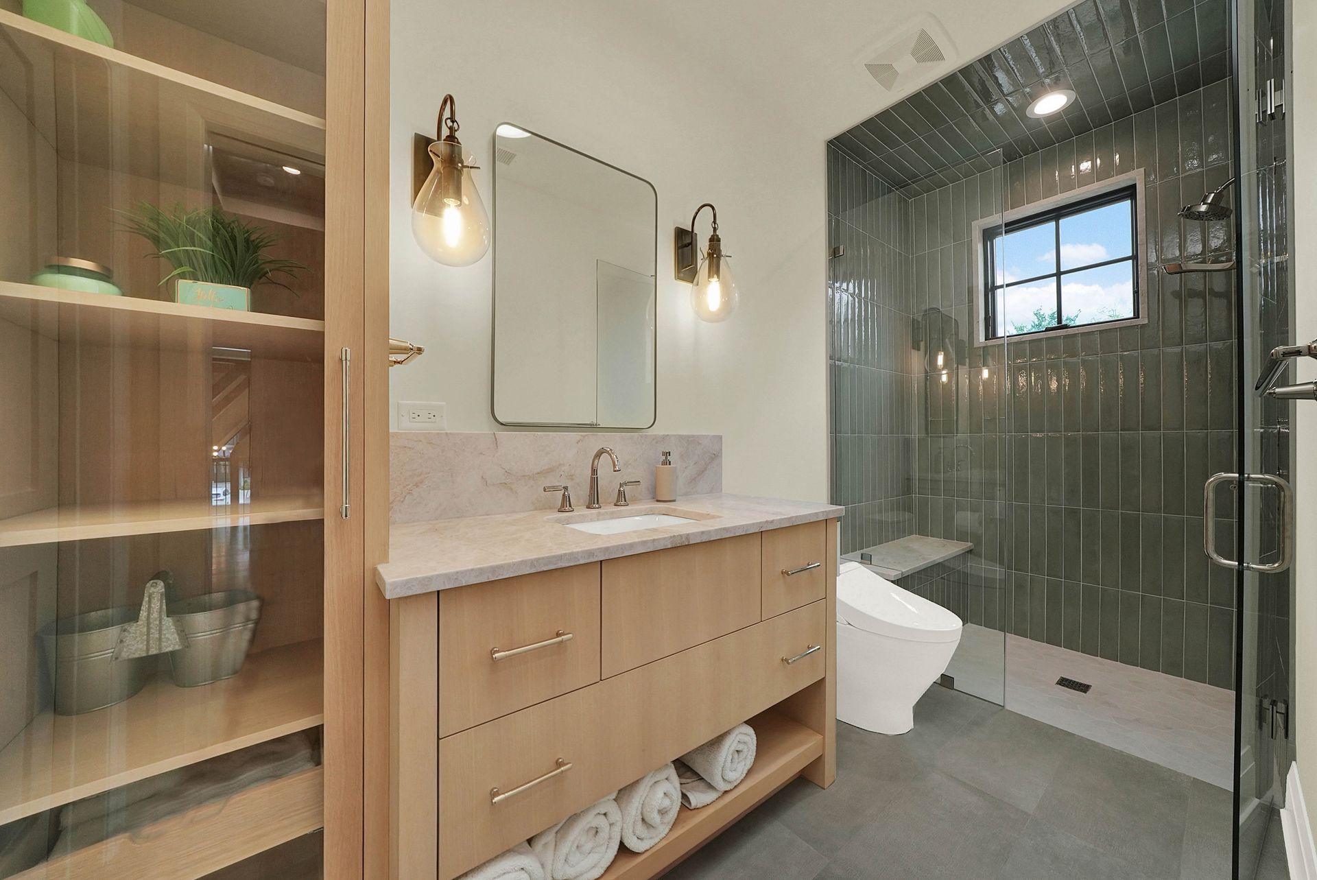 Modern bathroom with wood vanity, glass shower, and built-in shelving