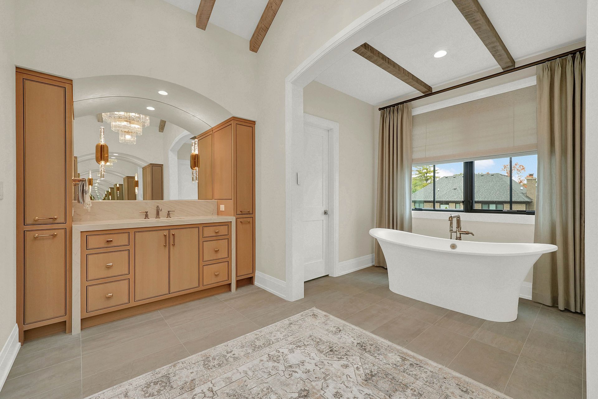 Spacious bathroom with double vanity, freestanding tub, vaulted ceiling, and large window.