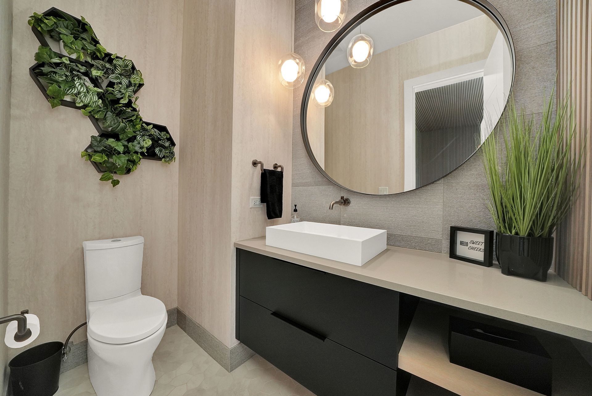 Modern bathroom with toilet, floating vanity, round mirror, sink, and green wall decor