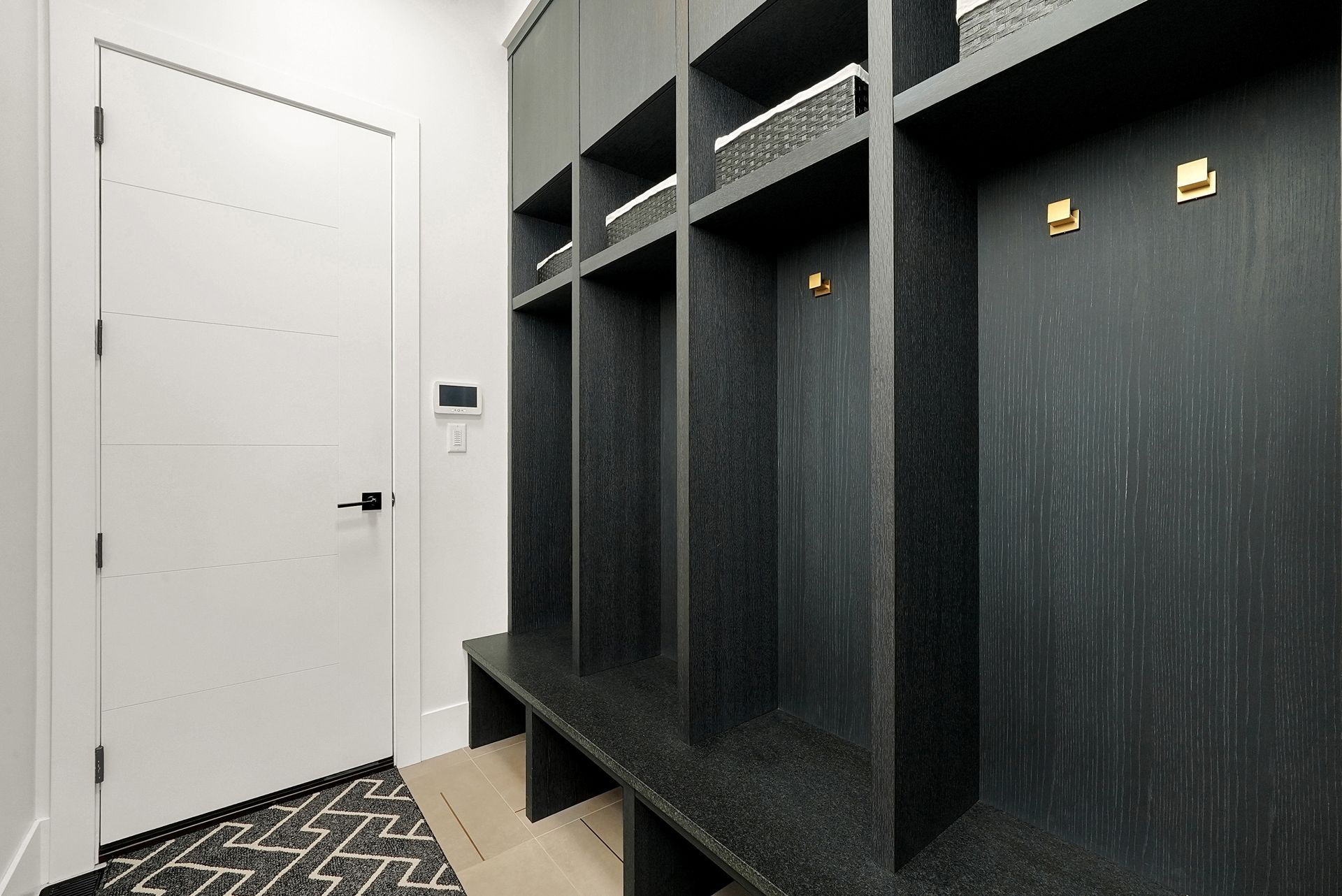 Modern entryway with white door, black shelving cubbies, and patterned rug