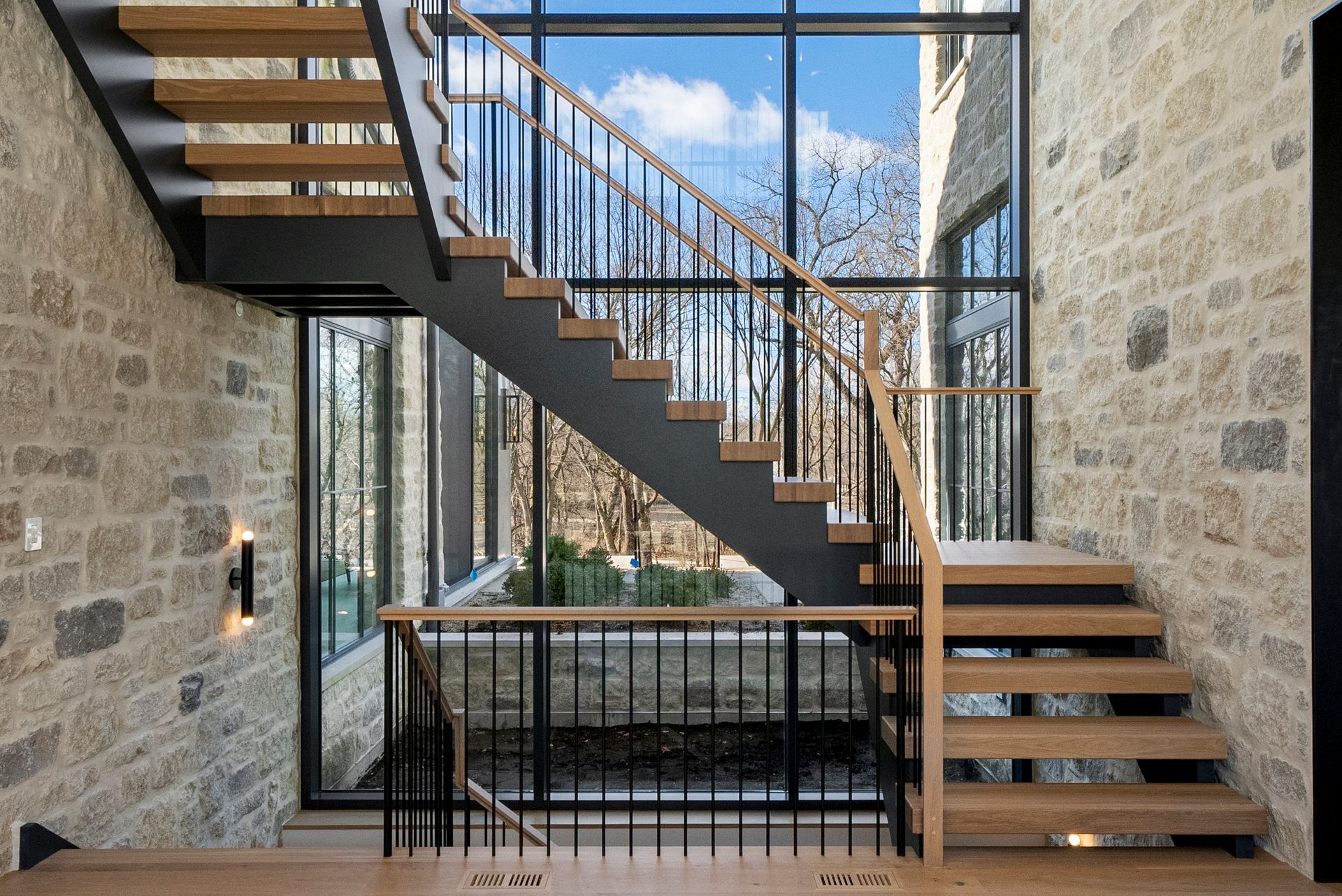 Modern stone staircase with black railings in a bright, open interior.