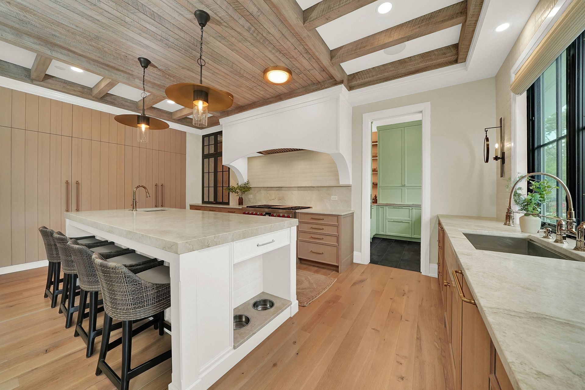 Modern kitchen with white island, wood floors, vaulted ceiling, and bar stools