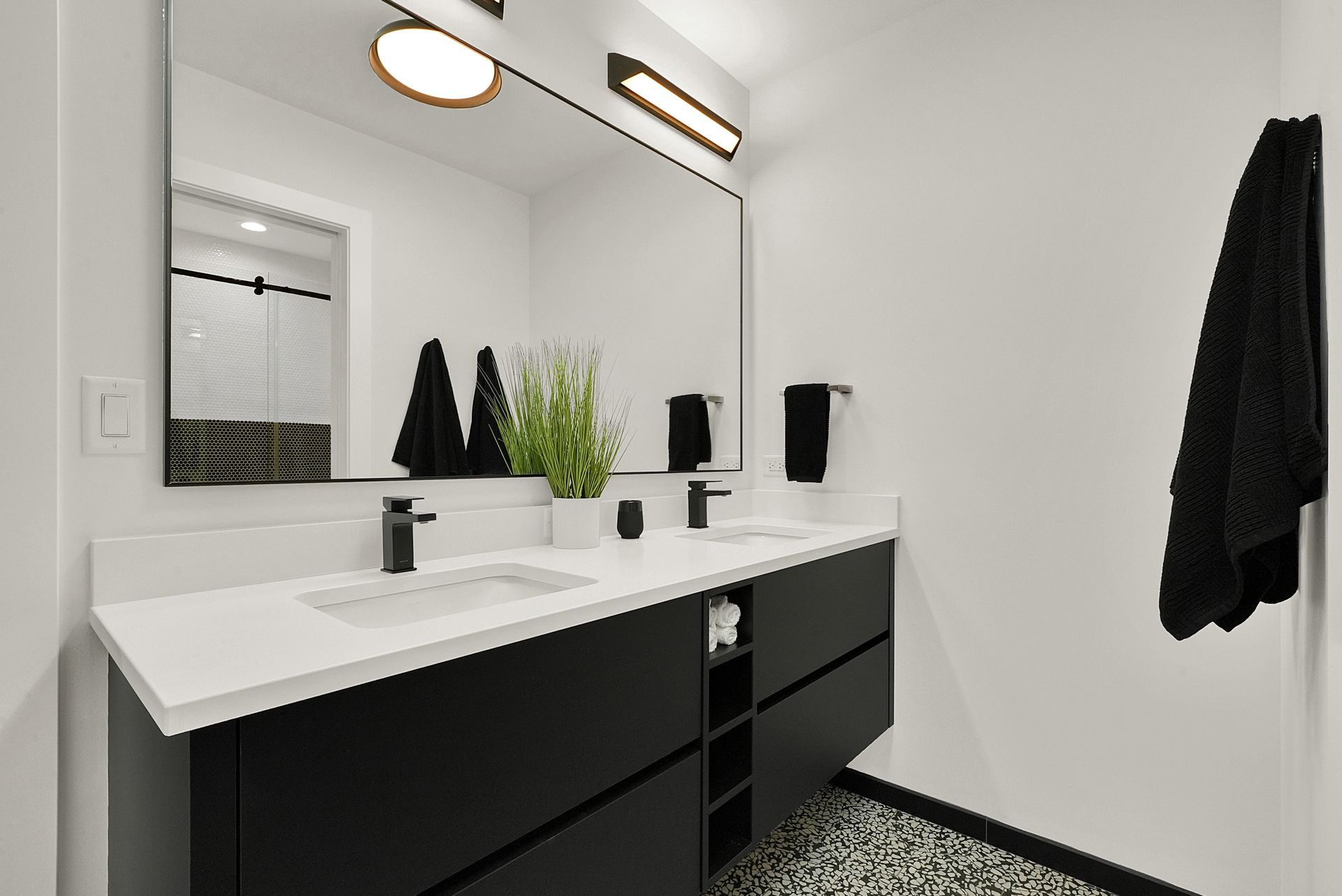 Modern black-and-white bathroom with double vanity, large mirror, and towel rack