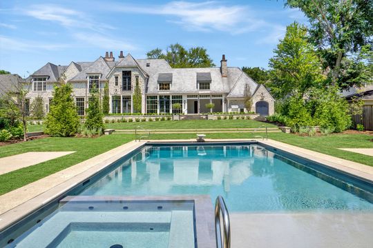 Luxury home with a rectangular swimming pool and hot tub in a landscaped backyard