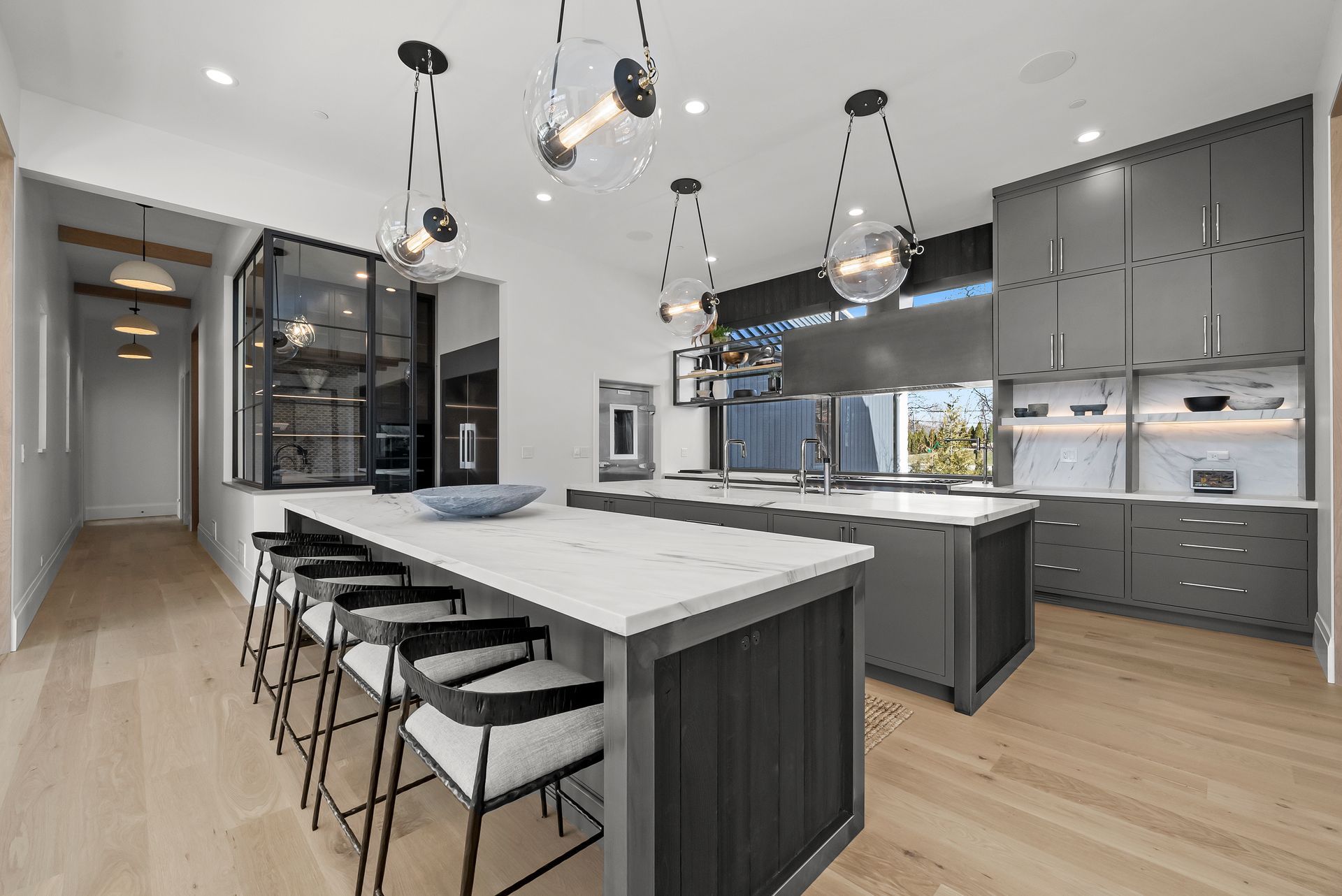 Modern kitchen with a large island, bar stools, pendant lights, and gray cabinets